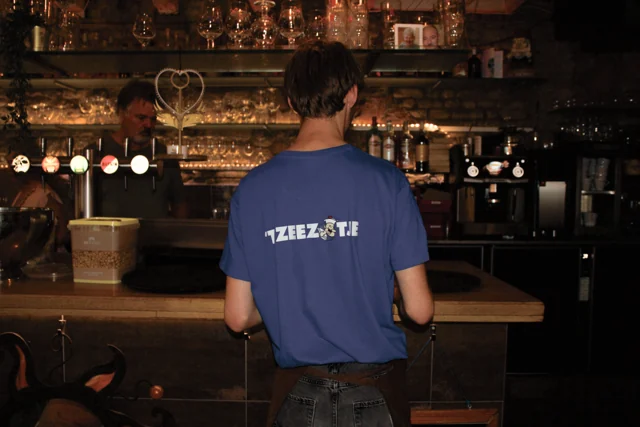 Een medewerker in Zeezotje-shirt aan de bar