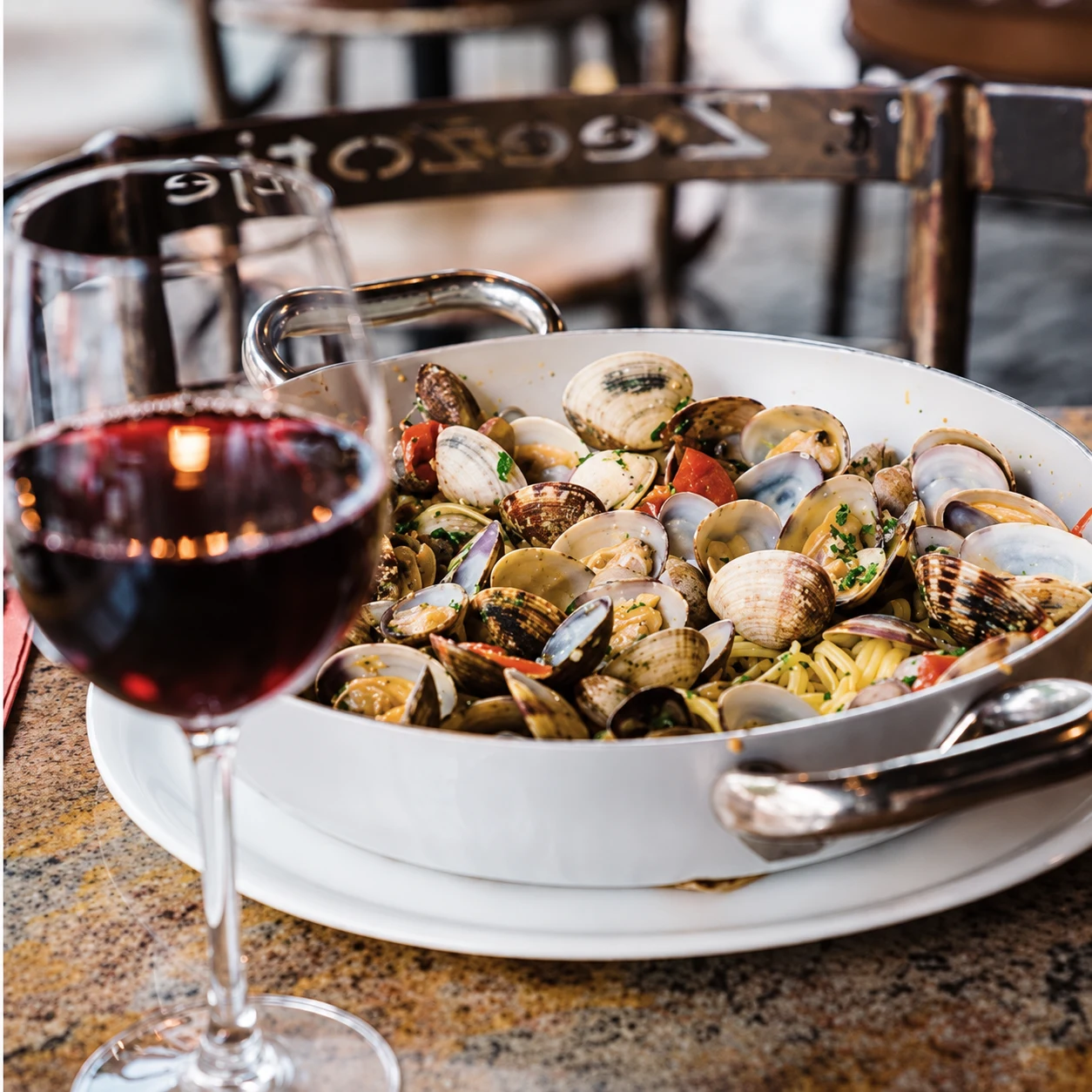 Tagliolini alle vongole met een glas rode wijn op tafel bij 't Zeezotje